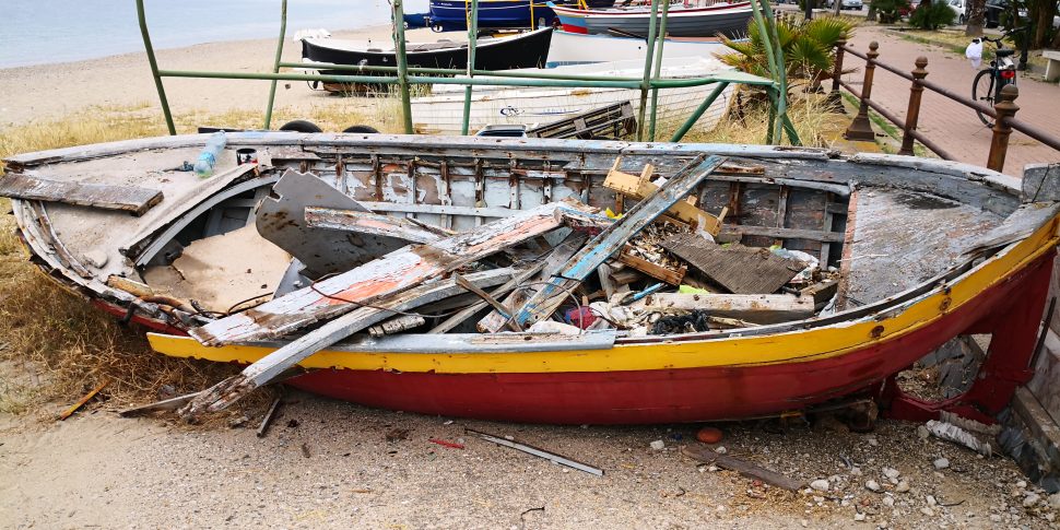 Barca abbandonata in spiaggia con rifiuti