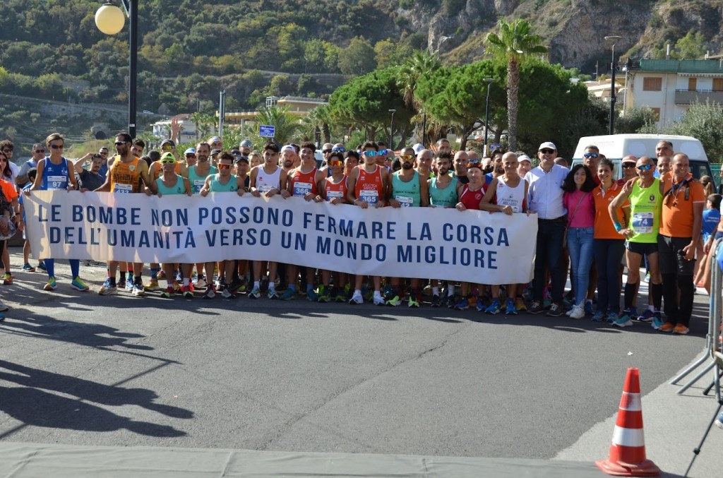 i partecipanti mostrano uno striscione prima della partenza dove si legge: "Le bombe non possono fermare la corsa dell'umanità verso un mondo migliore"